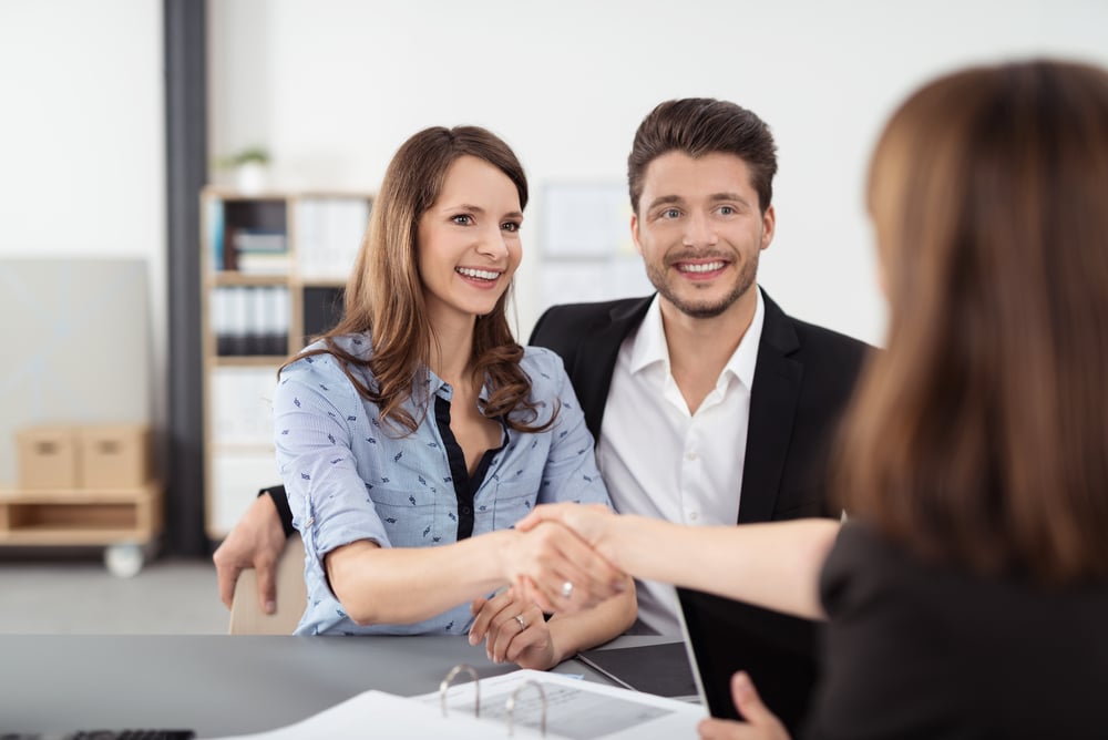 Happy Young Professional Couple Shaking Hands with a banker