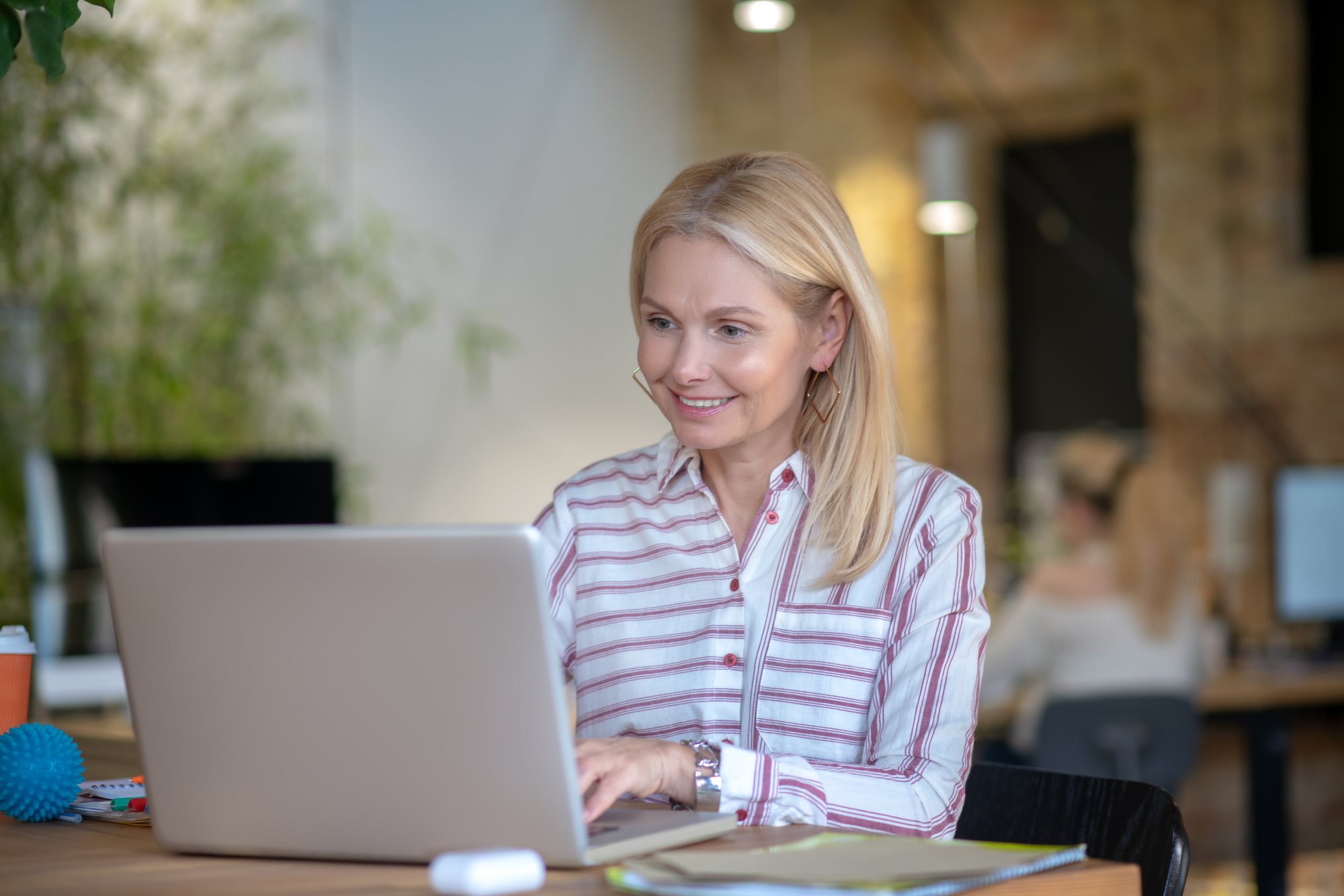 blonde-woman-sitting-at-desk-typing-on-laptop-sm-2024-10-18-03-30-46-utc