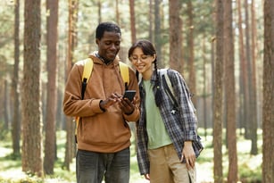 multiethnic-couple-using-mobile-phone-in-forest-2022-09-07-01-28-13-utc-1