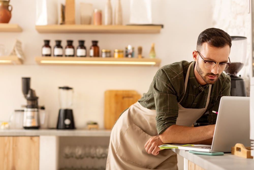 Small business owner working on his computer pulling together information to apply for a small business loan.