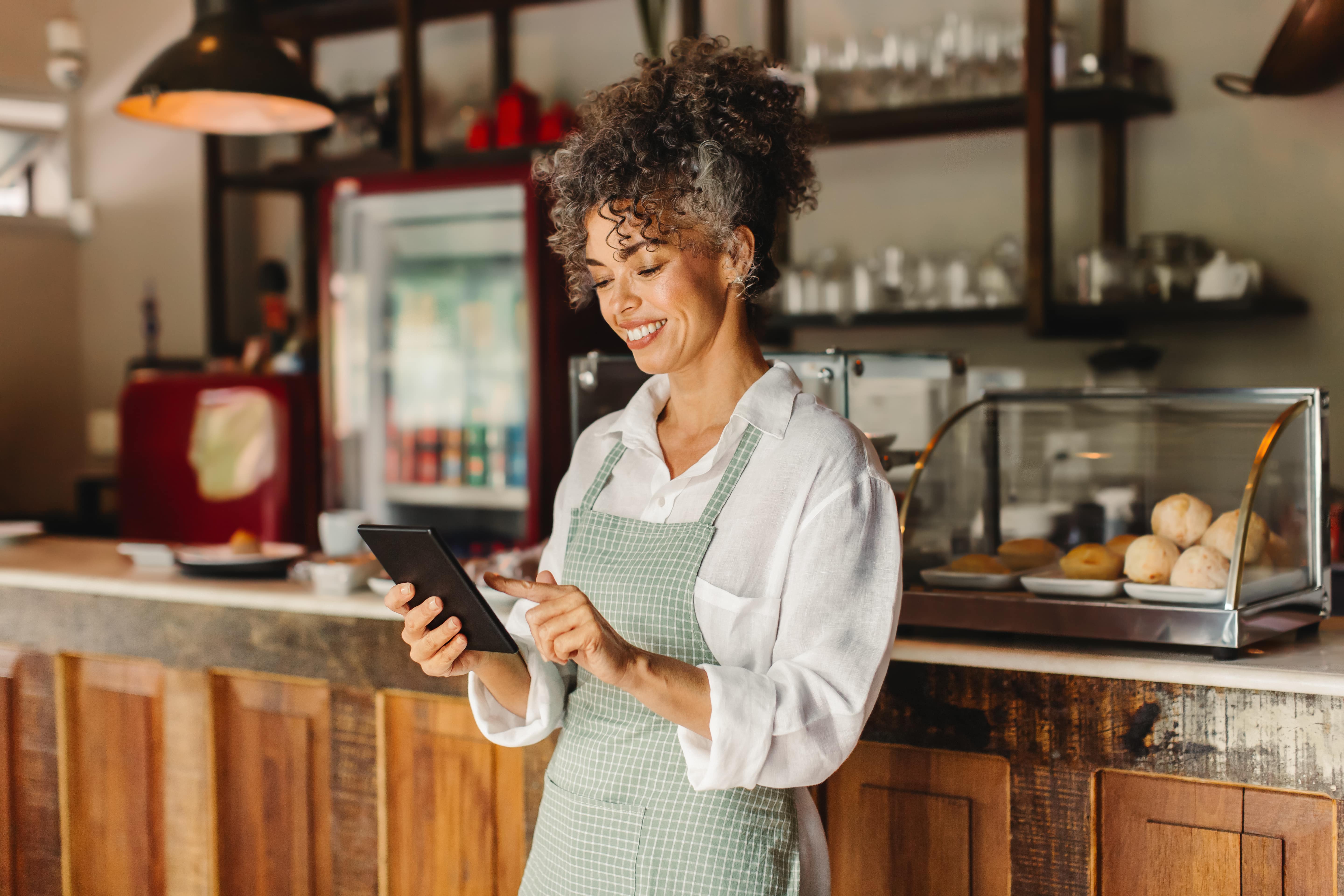 Woman in an apron smiling at phone