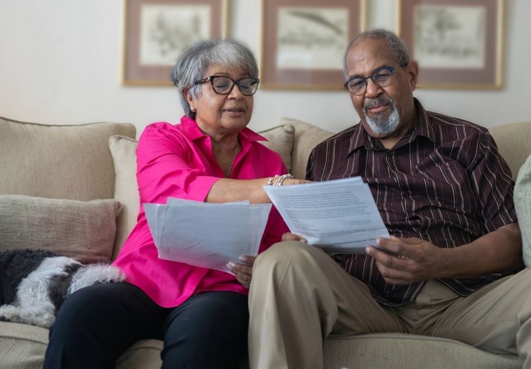 Older black couple sitting on a couch reviewing documents