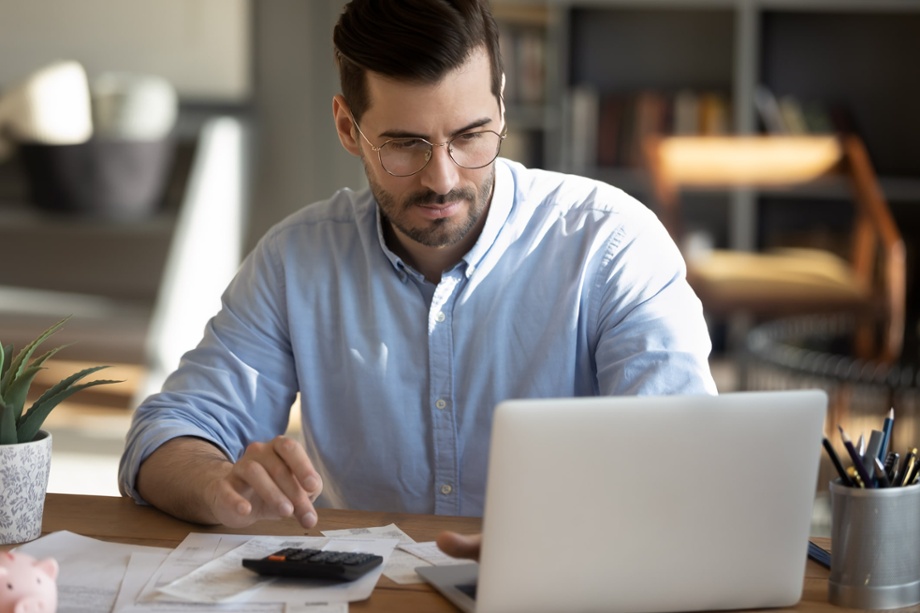 Man looking at a laptop and using a calculator