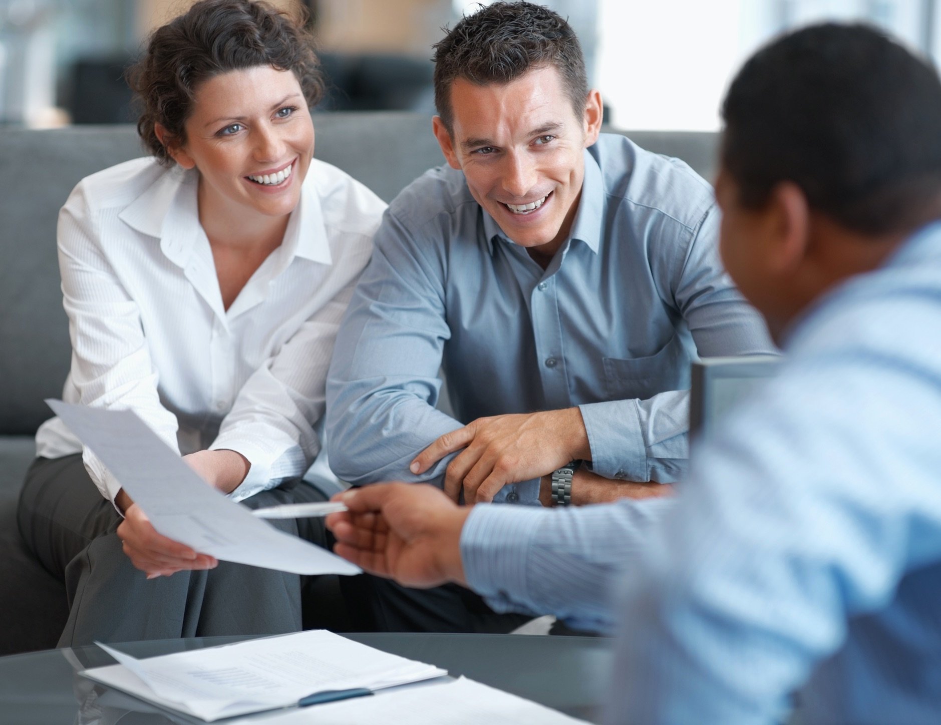 Smiling couple looking at paperwork with a trusted advisor