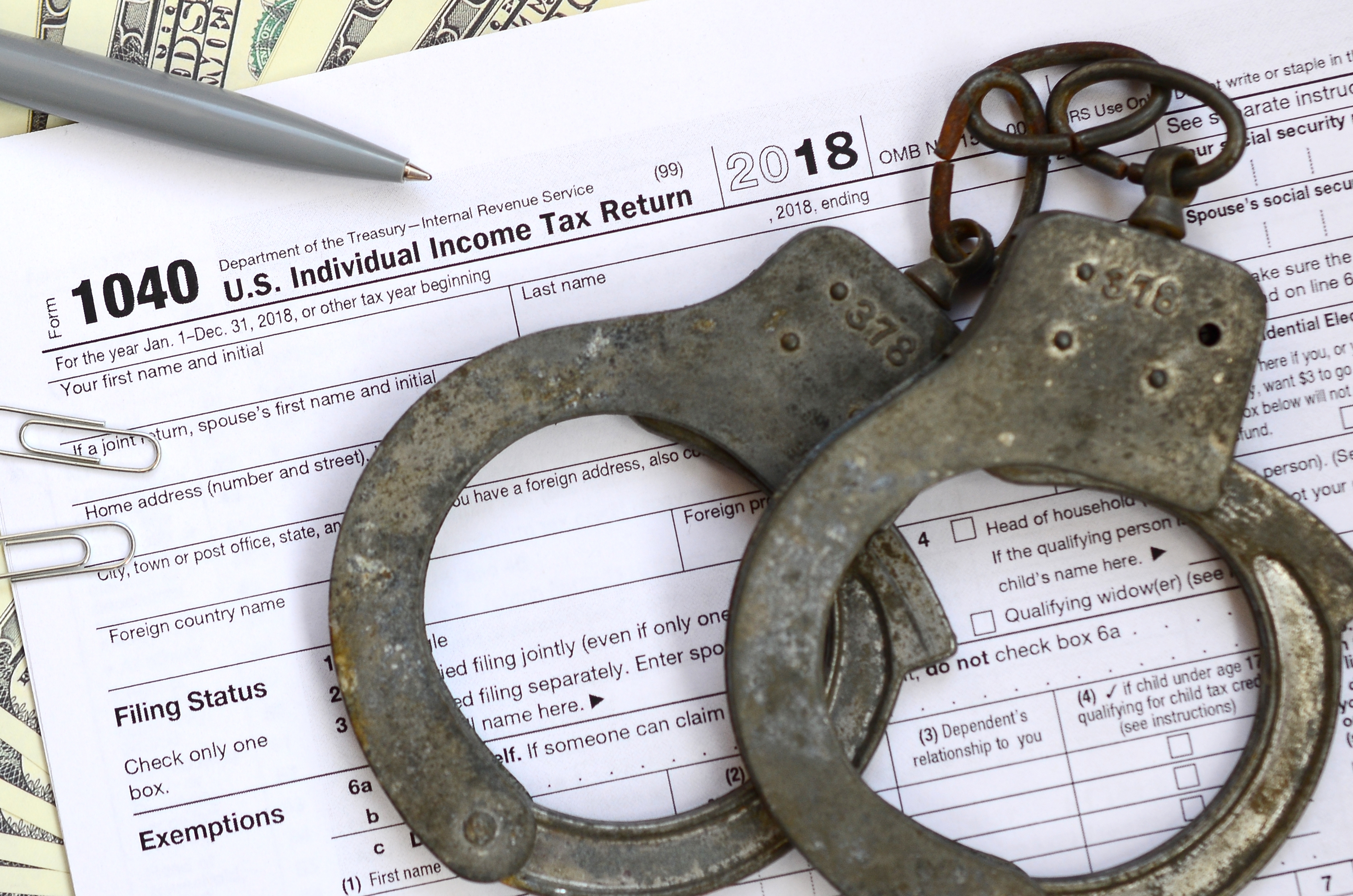 rusted handcuffs over tax forms