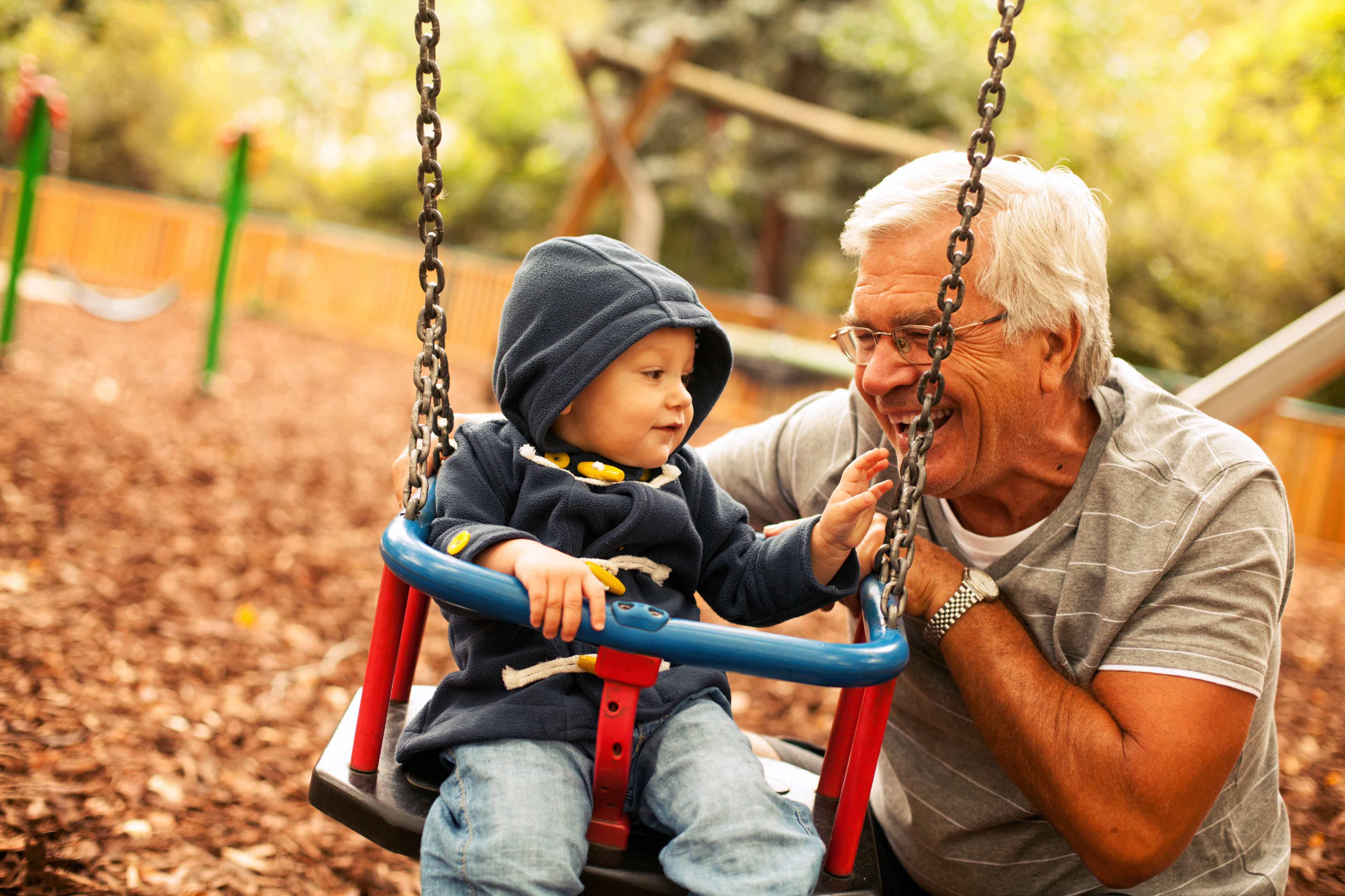grandpa pushes grandson on swing