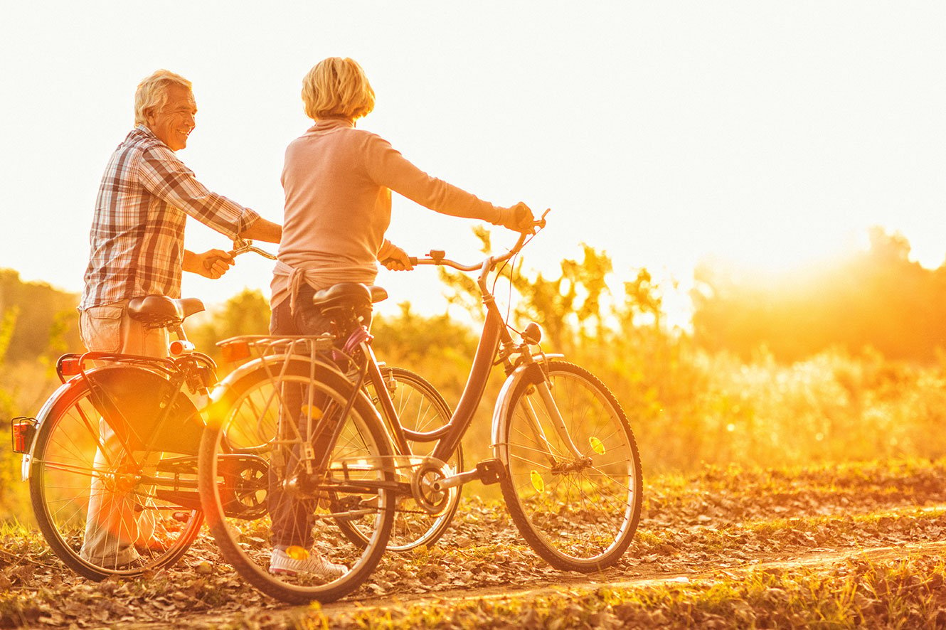 older couple biking at sunset