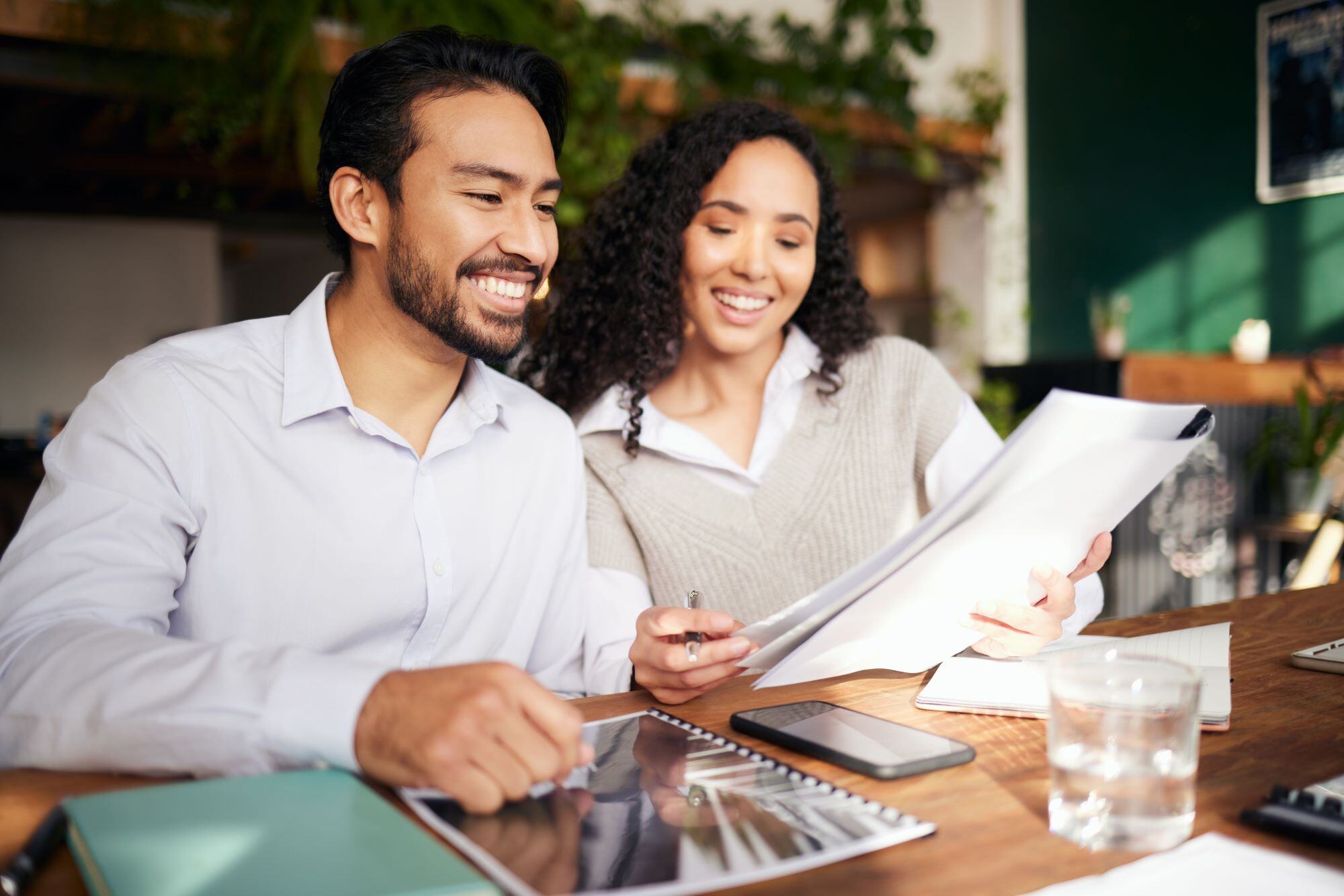 Smiling couple sitting together at a desk, reviewing papers