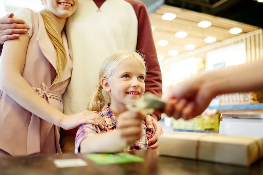 young girl giving money to a teller