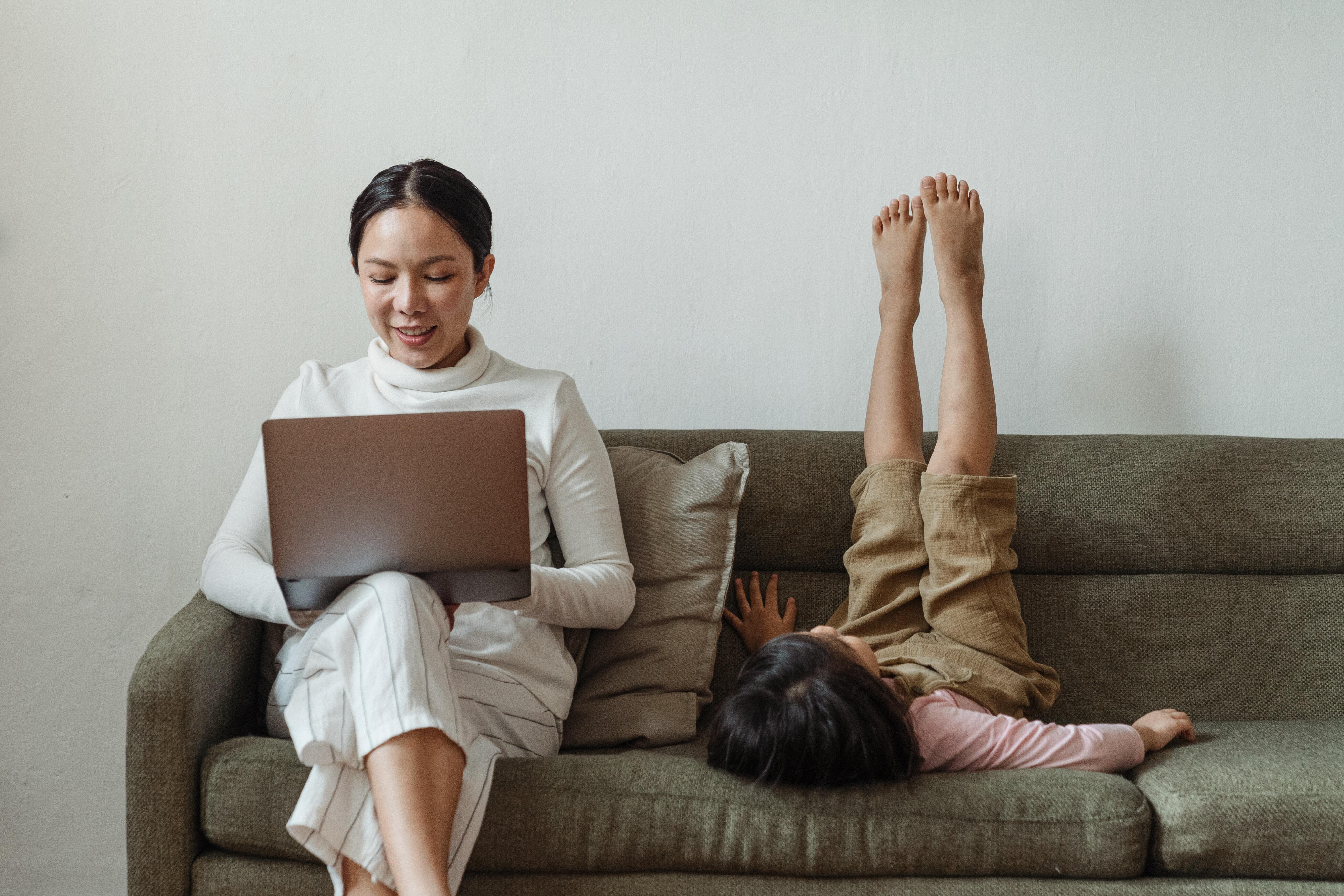 mom and kid sitting on the couch, kid upside down with legs in the air